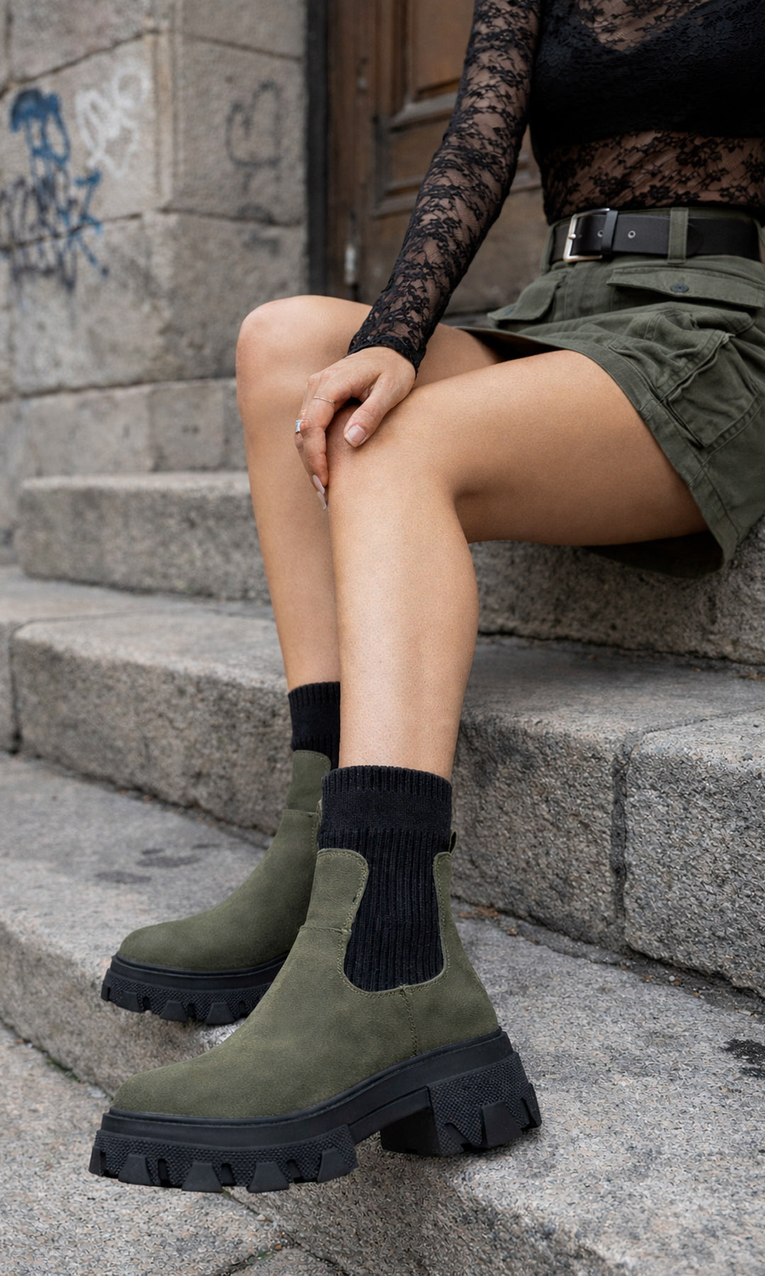 ASHTON LOOK URBAN SEXY COMBINANDO BOTINES COLOR VERDE OLIVO CON FALDA CORTA Y BLUSA NEGRA DE MALLA TRANSPARENTE PARA VERSE CHIC