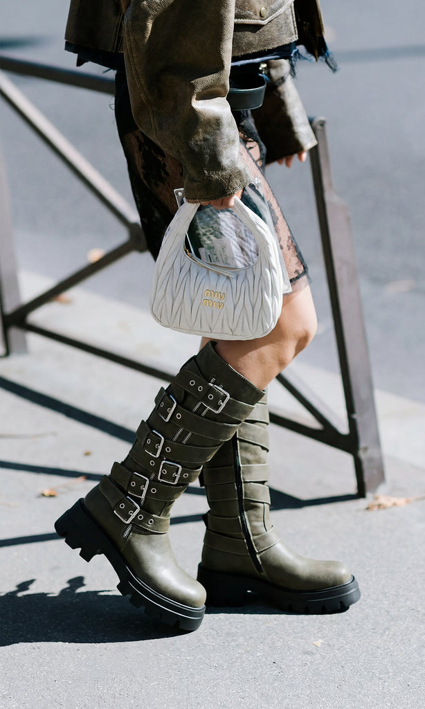 BIKER STREET STYLE LOOK COMBINANDO BOTAS VERDE OLIVO SUELA TRACK CON CAZADORA DE VINIPIEL ENCIMA DE VESTIDO NEGRO Y BOLSO BLANCO