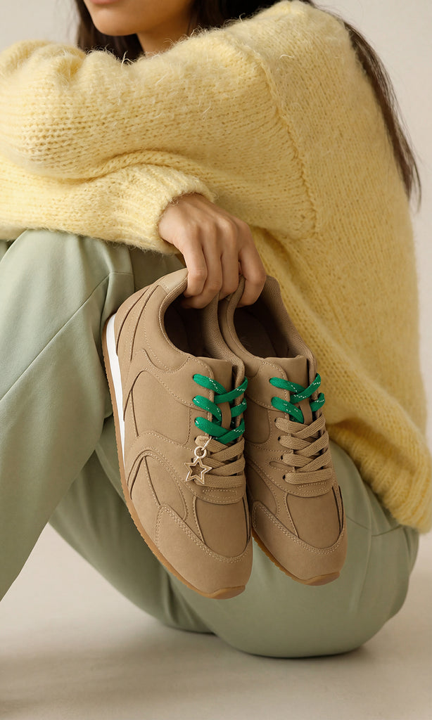 BROOKE CHICA SOSTIENE TENIS COLOR CAMEL MIENTRAS LUCE PANTALON COLOR VERDE Y SUETER AMARILLO PARA VERSE CHIC