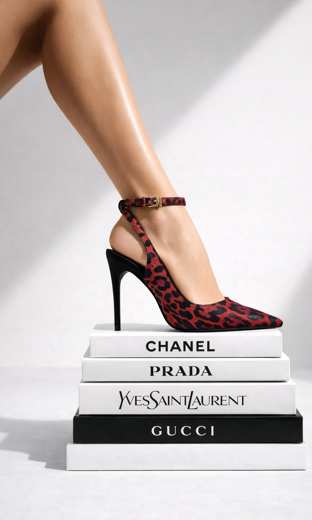 CITADEL MODELO POSA EN SESION FOTOGRAFICA ZAPATILLA SLINGBACK ROJA ESTAMPADO DE LEOPARDO MIENTRAS PISA LIBROS DE MODA