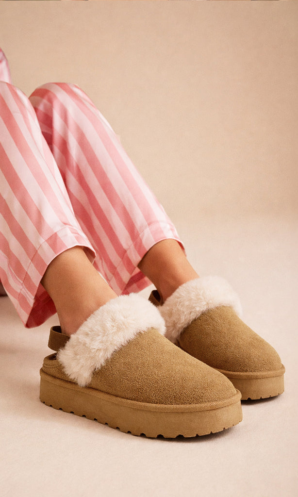 CLAIRE CHICA POSA EN CICLORAMA SNETADA PANTUFLAS CON PELUCHE ENFRENTE USANDO PIJAMA SATINADA DE LINEAS VESTICALES COLOR ROSA PARA PIJAMADA