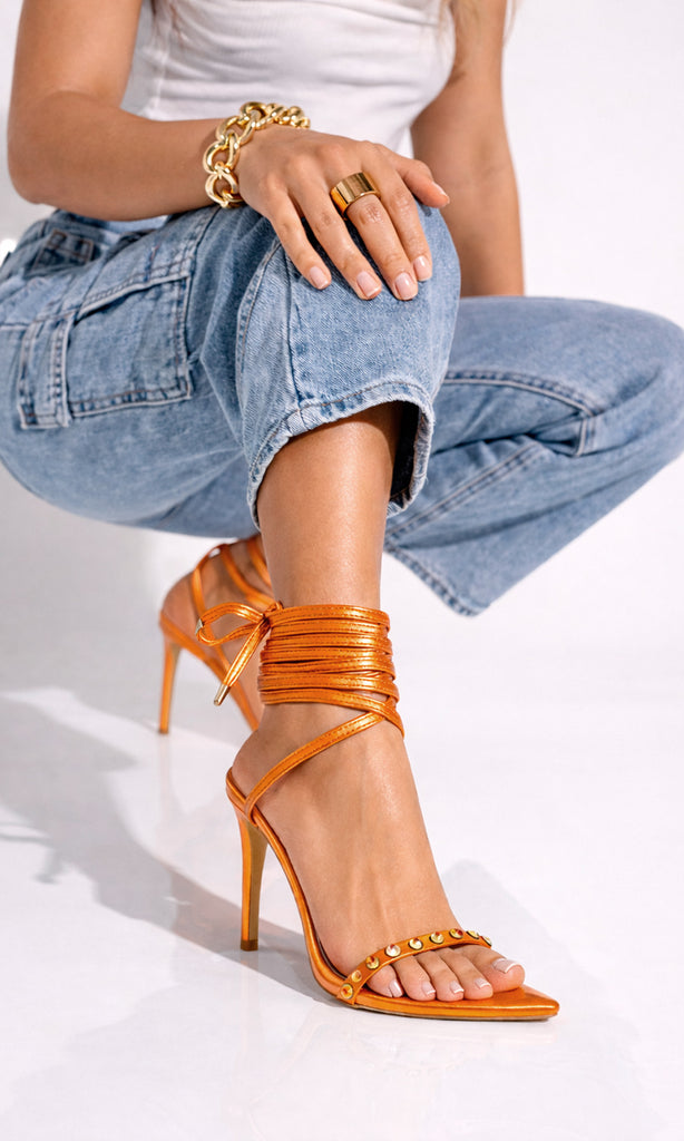 CONTROL MODELO POSA EN ESTUDIO FOTOGRAFICO MIENTRAS LUCE ZAPATILLAS NARANJAS DE LACE-UP Y PANTALONES DENIM A JUEGO CON PLAYERA BLANCA