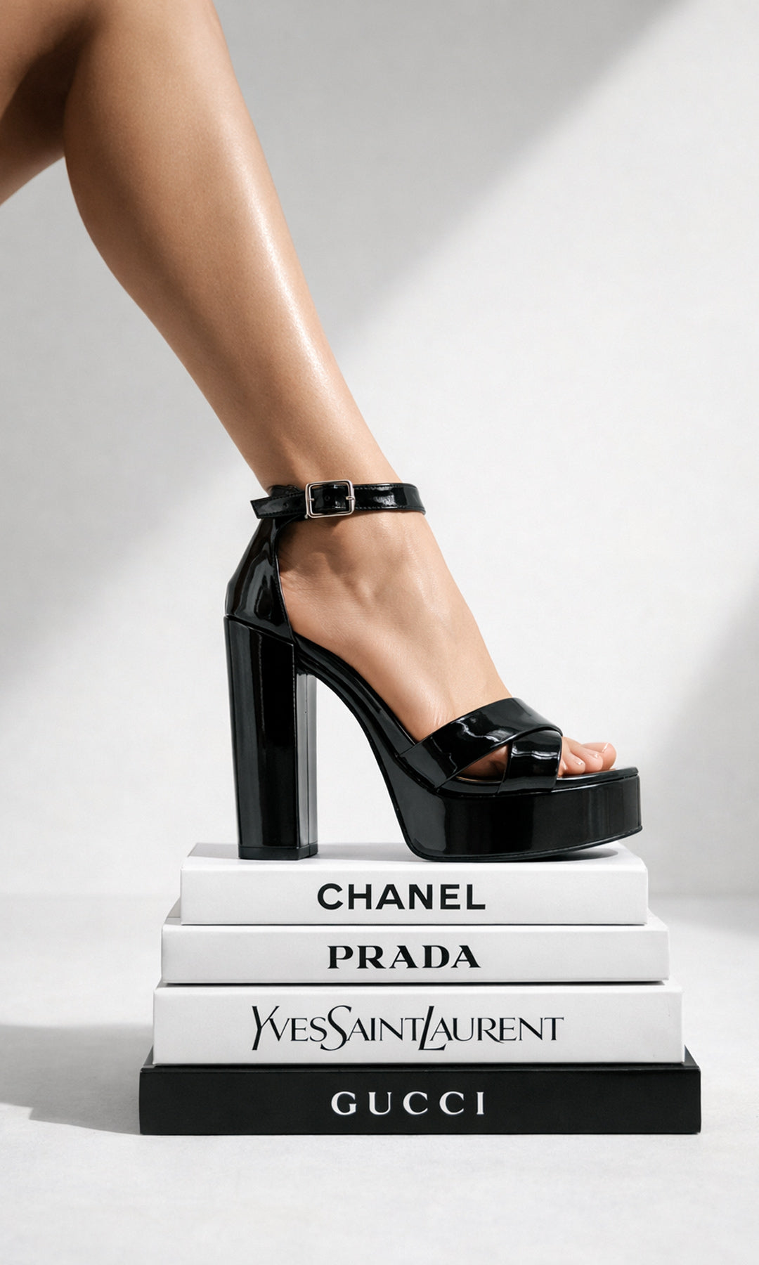 FIERCE MODELO POSA ZAPATILLAS NEGRAS DE CHAROL CON TACON CUADRADO MIENTRAS PISA LIBROS DE MODA Y LUCE FASHION