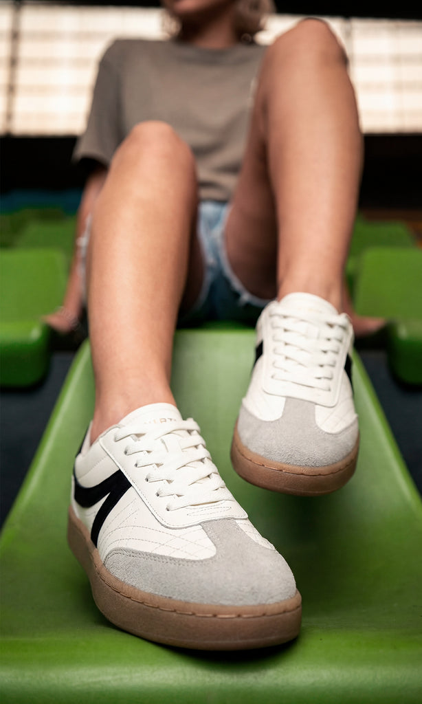 GIANNA CHICA POSA SENTADA SNEAKERS BLANCOS CON SHORT DE MEZCLILLA Y PLAYERA GRIS OVERSIZE PARA VERSE TRENDY EN SALIDA CON AMIGAS