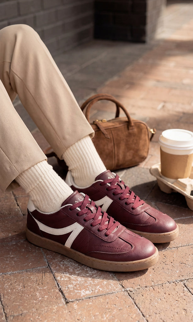 GIANNA CHICA USA SNEAKERS COLOR VINO CON CALCETAS BLANCAS VISIBLES Y PANTALON COLOR ARENA A JUEGO CON BOLSO CAFE DE MANO PARA VERSE CHIC