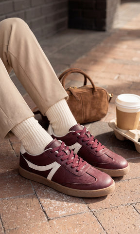GIANNA CHICA USA SNEAKERS COLOR VINO CON CALCETAS BLANCAS VISIBLES Y PANTALON COLOR ARENA A JUEGO CON BOLSO CAFE DE MANO PARA VERSE CHIC