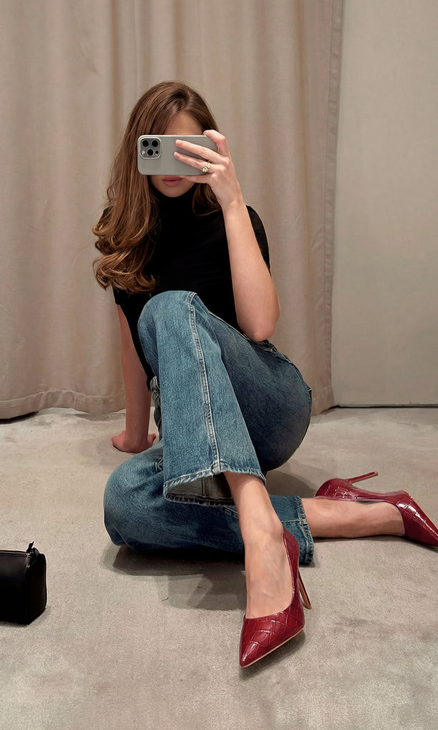 KENYA CHICA CÓMO COMBINAR ZAPATILLAS ROJO VINO ACABADO CROC CON PANTALON DE MEZCLILLA Y TOP NEGRO MIENTRAS SOSTIENE CELULAR PARA CUBRIR SU ROSTRO