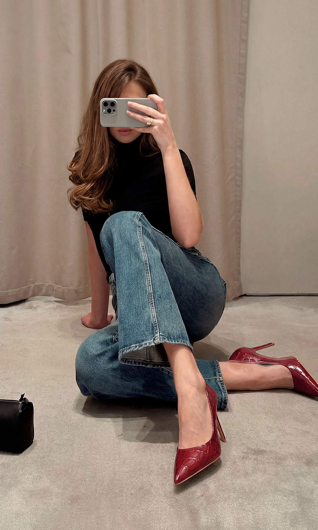 KENYA CHICA CÓMO COMBINAR ZAPATILLAS ROJO VINO ACABADO CROC CON PANTALON DE MEZCLILLA Y TOP NEGRO MIENTRAS SOSTIENE CELULAR PARA CUBRIR SU ROSTRO