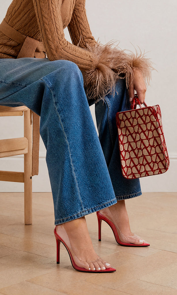 MAGIC CHICA COMBINA STILETTOS ROJOS DE MICA TRANSPARENTE CON PANTALON DE MEZCLILLA Y SUETER CAFE MIENTRAS SOSTIENE BOLSO DE MANO 