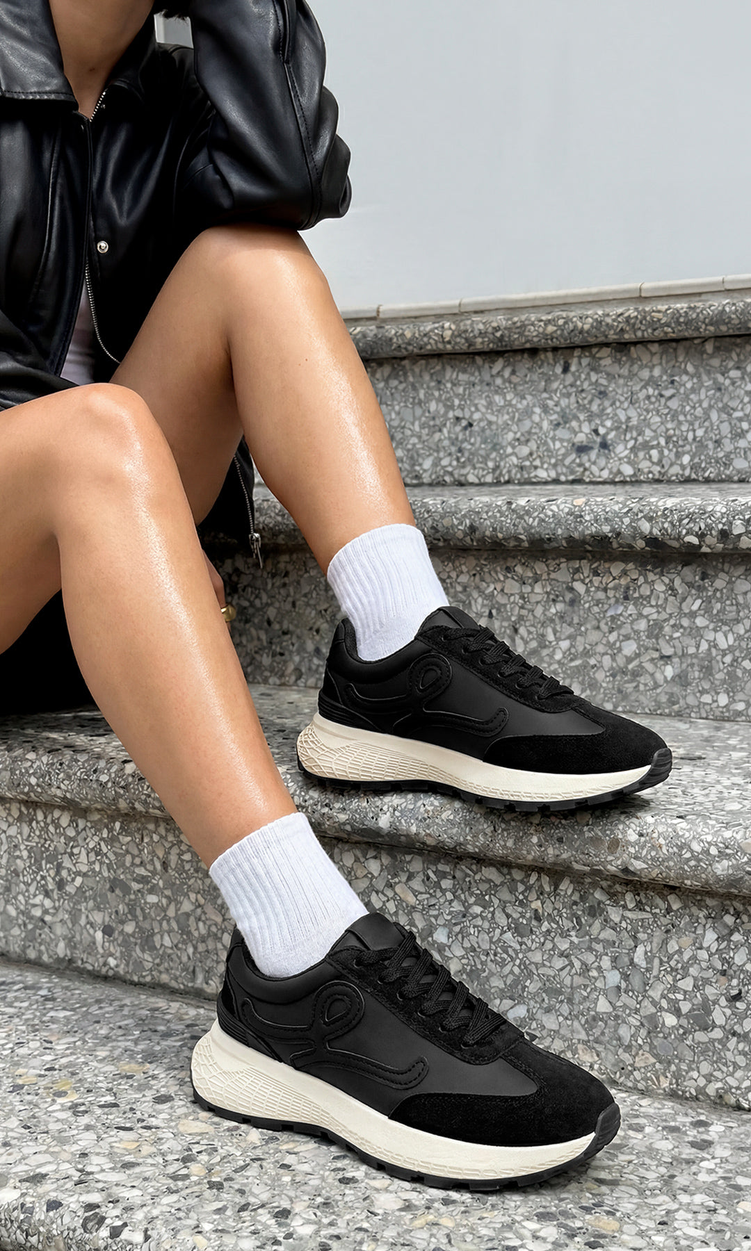 MELINE OUTFIT PARA USAR EN LA UNIVERSIDAD LUCIENDO SNEAKERS NEGROS CON CALCETAS BLANCAS Y CHAMARRA DE CUERO ENCIMA DE T-SHIRT CON SHORT