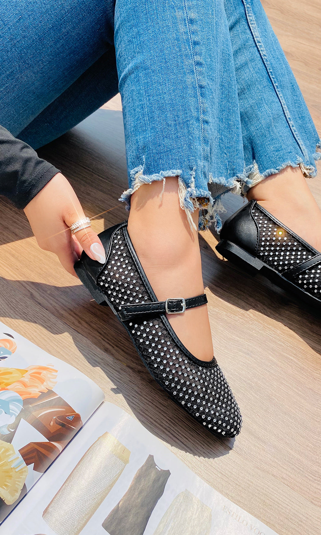 MIRANDA MODELO POSA SOBRE PISO DE MADERA BALLERINAS NEGRAS DE MESH CON BRILLOS Y PANTALON DE MEZCLILLA PARA USAR EN PRIMAVERA