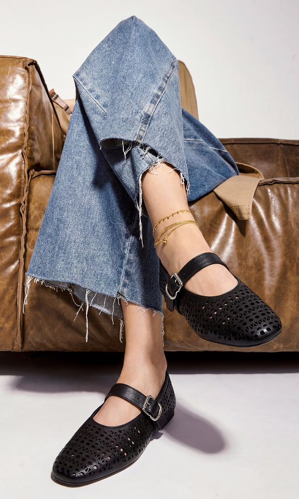PENNY CÓMO COMBINAR ZAPATOS NEGROS MARY JANE LASER CUT CON PANTALONES DE MEZCLILLA MIENTRAS POSA SENTADA EN SILLON VINTAGE