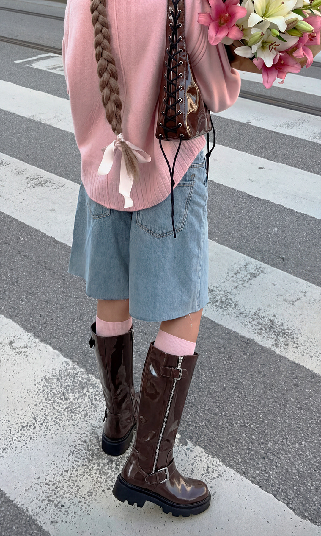 RIDER LOOK PARA SALIR CON AMIGAS LUCIENDO BOTAS CAFES DE SUELA TRACK Y SHORT CAPRI CON SUETER ROSA MIENTRAS SOSTIENE FLORES