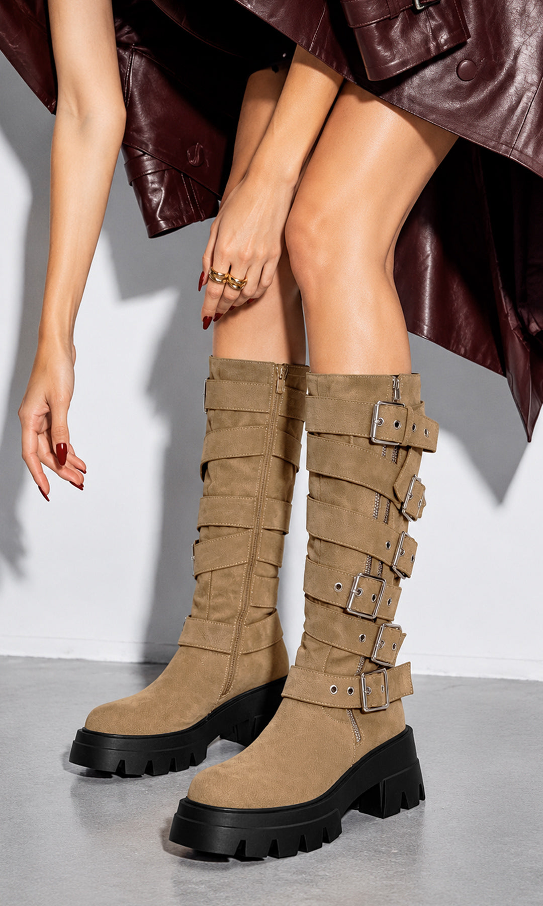Bota Biker alta en tono nude, con acabado tipo gamuza, varias correas horizontales con grandes hebillas metálicas, detalles de cierre y suela track negra de plataforma gruesa con tacón robusto