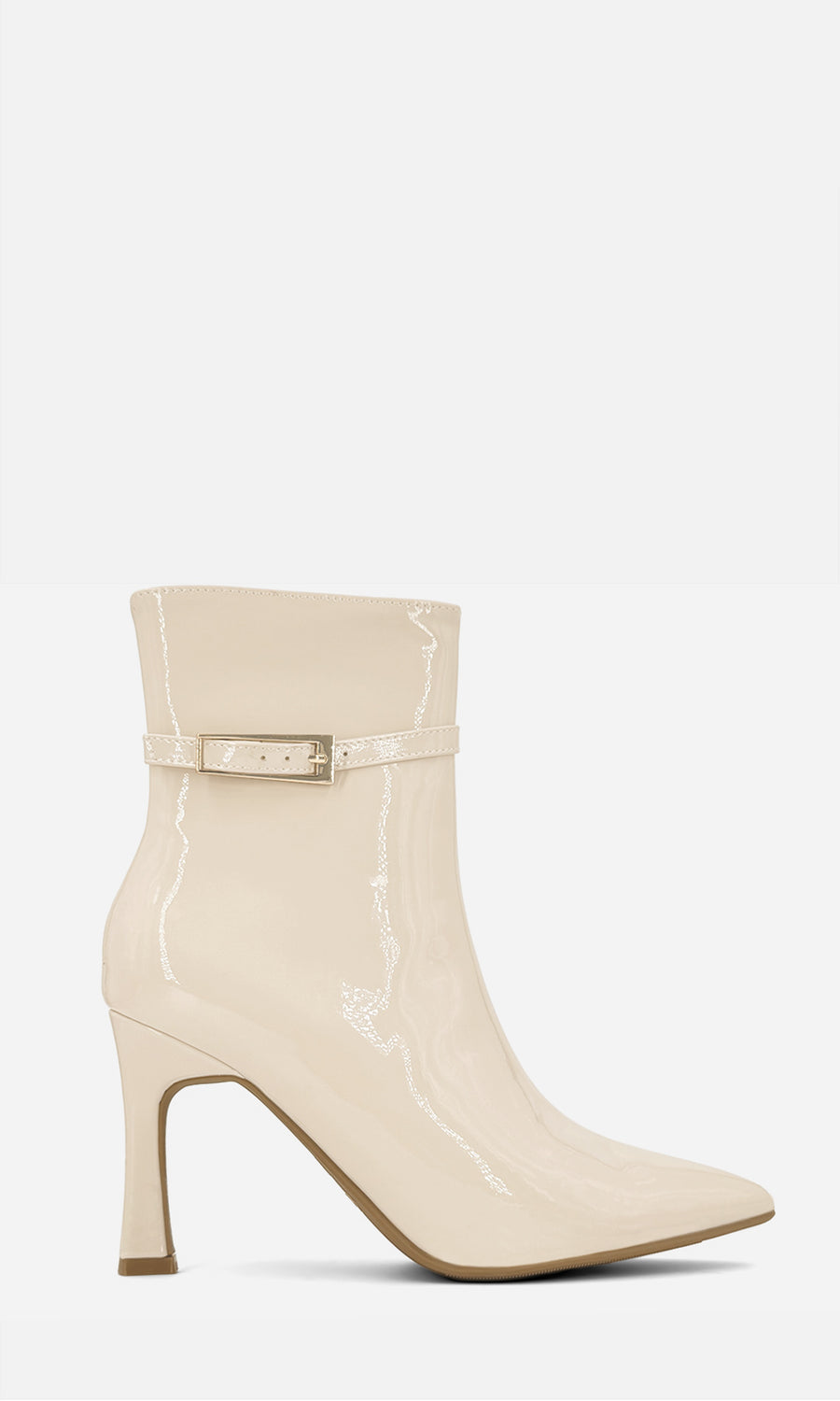 Botines blanco marfil de charol con punta afilada, tacón fino y detalle de hebilla al tobillo, combinados con falda negra de volantes, suéter café y bolso negro