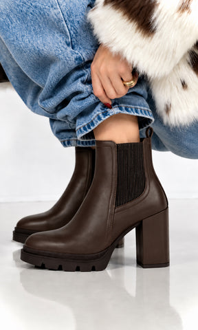 Botines café para mujer estilo Chelsea con paneles elásticos laterales, tacón alto de bloque y suela track con plataforma, combinados con jeans amplios de mezclilla azul en un look casual de temporada