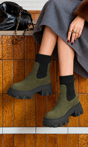 Botines Chelsea Ashton verde olivo con tejido elástico negro en la caña, tirador posterior y suela dentada negra de gran volumen, combinados con falda gris