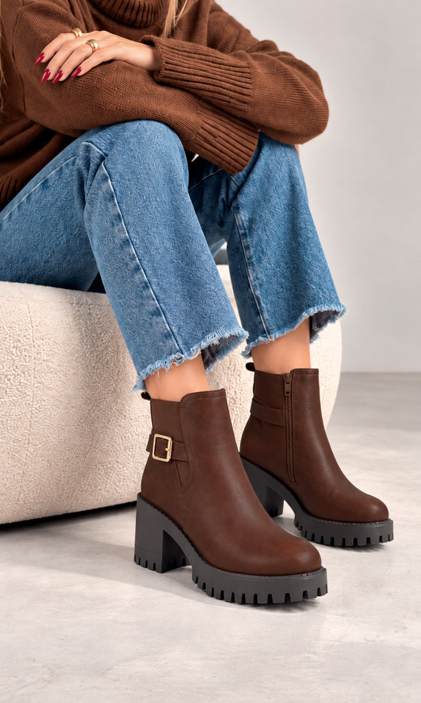 Botines Paula café con hebilla lateral dorada, tacón bloque y suela track negra de gran volumen, combinados con jeans de corte amplio y suéter café