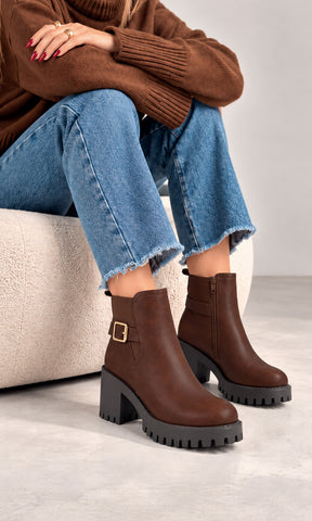 Botines Paula café con hebilla lateral dorada, tacón bloque y suela track negra de gran volumen, combinados con jeans de corte amplio y suéter café