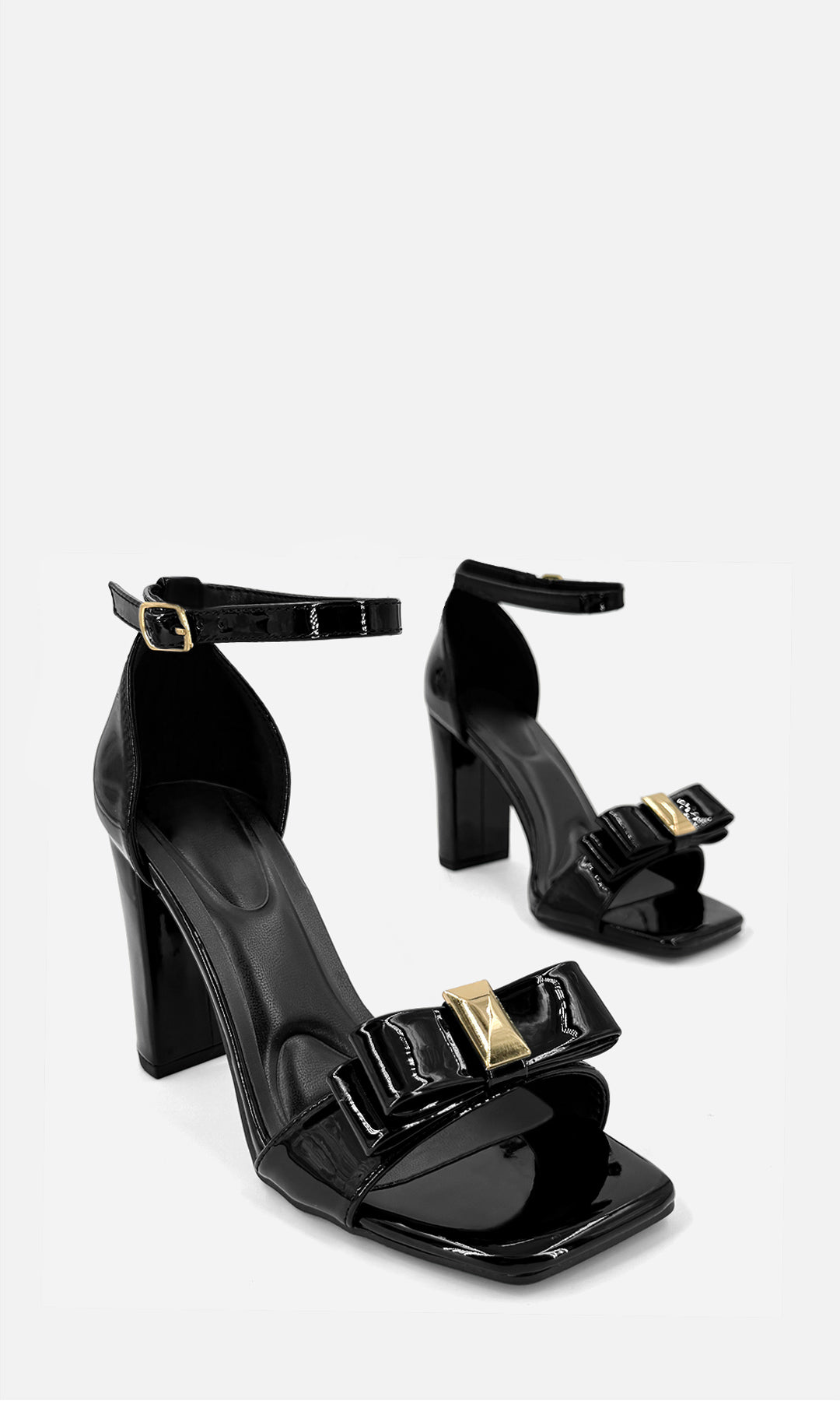 Par de zapatillas de tacón CHERRY NEGRO de charol en vista 3/4, con punta cuadrada, moño frontal con detalle dorado, pulsera al tobillo y tacón ancho de 9.5 cm