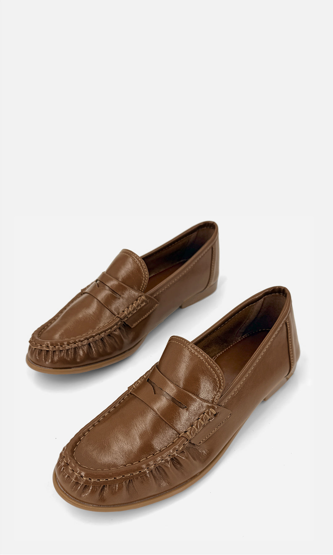 Par de mocasines tipo penny loafer DANDY CAMEL de vinipiel en vista 3/4, con antifaz frontal, costuras tipo mocasín y tacón bajo de 1.5 cm