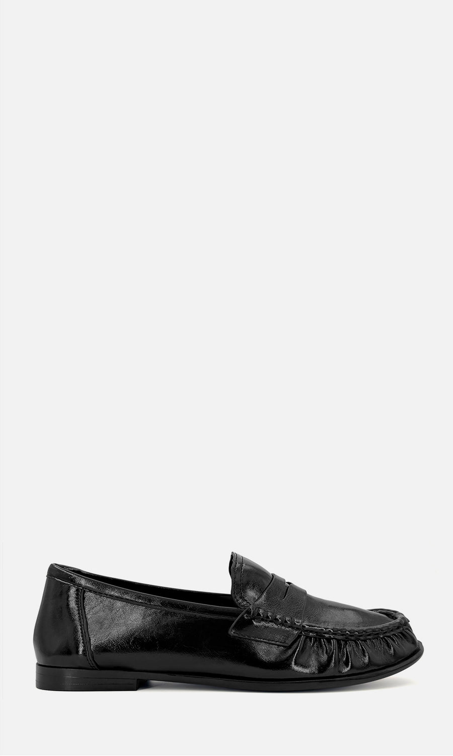 Mocasines Dandy negros de acabado brillante con antifaz y detalle fruncido en la punta, combinados con calcetas beige y abrigo gris