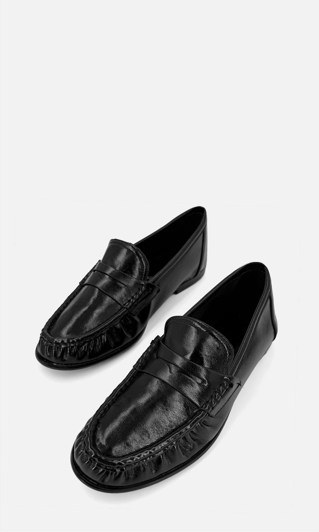 Par de mocasines tipo penny loafer DANDY NEGRO de vinipiel en vista 3/4, con antifaz frontal, costuras marcadas y tacón bajo de 1.5 cm