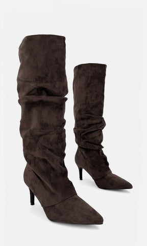Par de botas altas tipo slouch FRAN CAFÉ de gamuza en vista 3/4, con caña drapeada, punta afinada y tacón fino de 7.5 cm