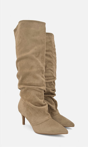 Par de botas altas tipo slouch FRAN TAUPE de gamuza en vista 3/4, con caña drapeada, punta afinada y tacón fino de 7.5 cm