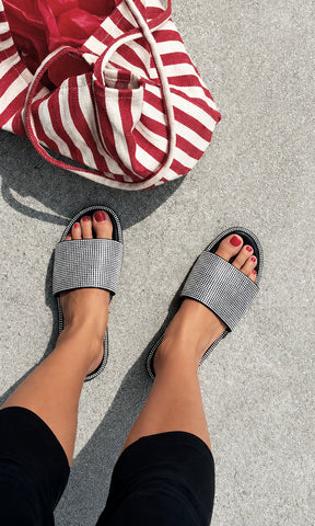 Sandalias de brillos INGRID negras con pedrería plateada, combinadas con un look casual en negro y bolso de rayas para un outfit de verano cómodo y moderno