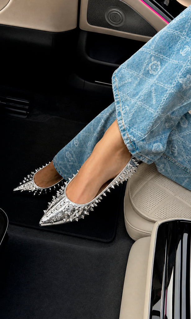 Flats KENDRA plateados con acabado metálico y estoperoles, ideales para aportar un toque moderno a looks casuales con jeans.