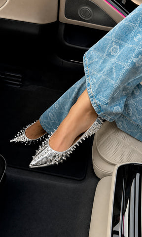Flats KENDRA plateados con acabado metálico y estoperoles, ideales para aportar un toque moderno a looks casuales con jeans.