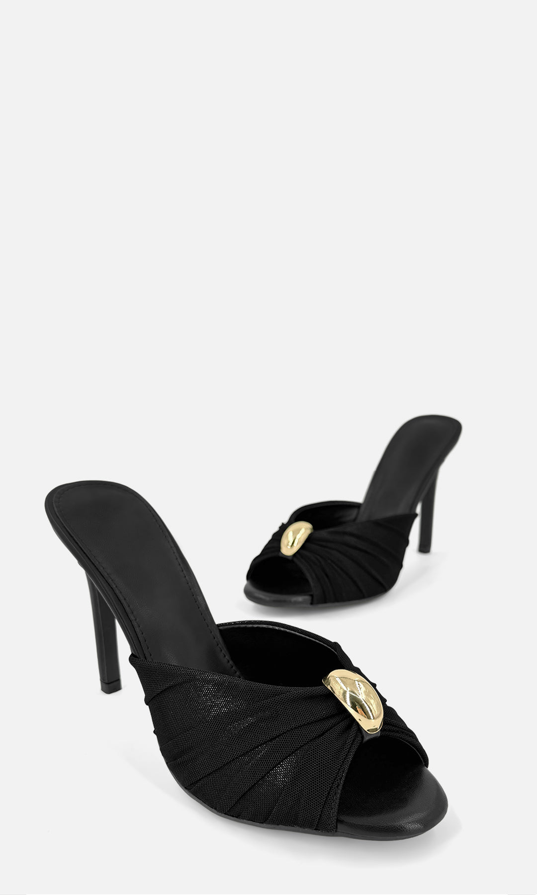 Par de zapatillas mule MALIBU NEGRO en vista 3/4, con mesh negro, joyería 3D dorada al frente, punta abierta y tacón fino de 10.5 cm