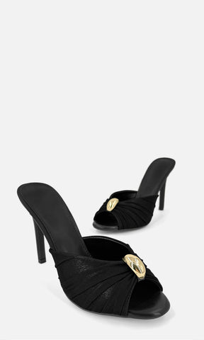 Par de zapatillas mule MALIBU NEGRO en vista 3/4, con mesh negro, joyería 3D dorada al frente, punta abierta y tacón fino de 10.5 cm