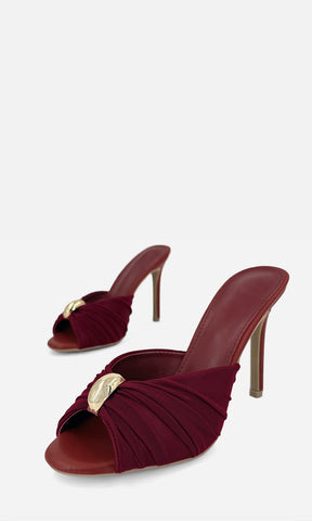 Par de zapatillas mule MALIBU VINO en vista 3/4, con mesh color vino, joyería 3D dorada al frente, punta abierta y tacón fino de 10.5 cm