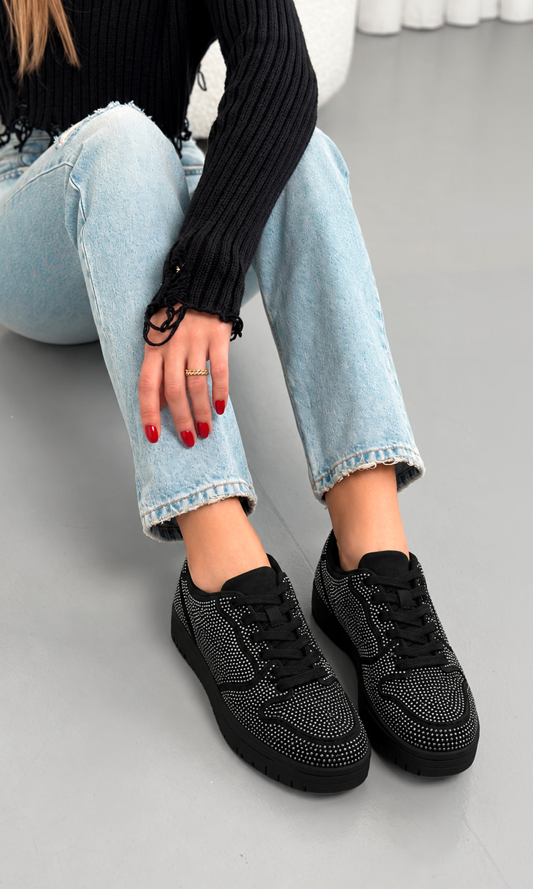 Tenis Mariselle negros de plataforma baja con agujetas y aplicaciones de cristales brillantes, combinados con jeans claros
