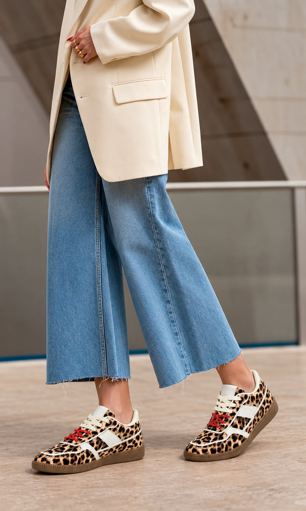 Sneakers Matcha con estampado de leopardo, silueta retro de perfil bajo, paneles blancos en contraste, agujetas rojos y suela de goma combinados con jeans cropped de pierna ancha