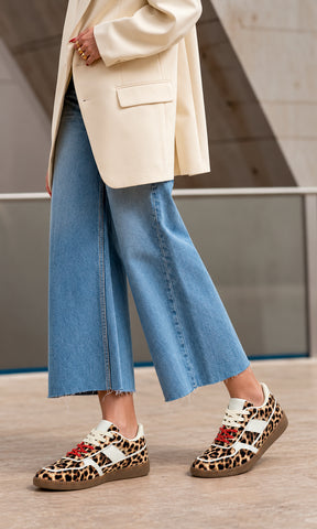 Sneakers Matcha con estampado de leopardo, silueta retro de perfil bajo, paneles blancos en contraste, agujetas rojos y suela de goma combinados con jeans cropped de pierna ancha