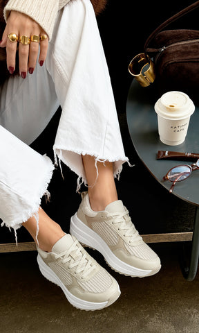 Sneakers Naomi color blanco marfil con paneles de malla y suela elevada, combinados con jeans blancos en estilo casual 