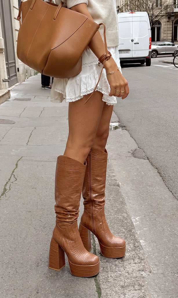 Botas REX color camel con acabado tipo cocodrilo, plataforma alta y tacón ancho, combinadas con vestido blanco y bolso camel para un look urbano
