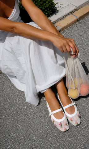 Flats SUGAR blancos tipo Mary Jane con mesh transparente y flores bordadas, combinados con vestido blanco para un look fresco y femenino.