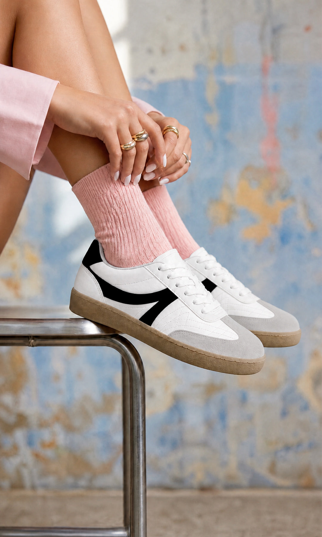 Tenis blancos estilo retro con detalles negros y suela color caramelo, combinados con calcetas rosas y prendas en tonos pastel para un look casual juvenil