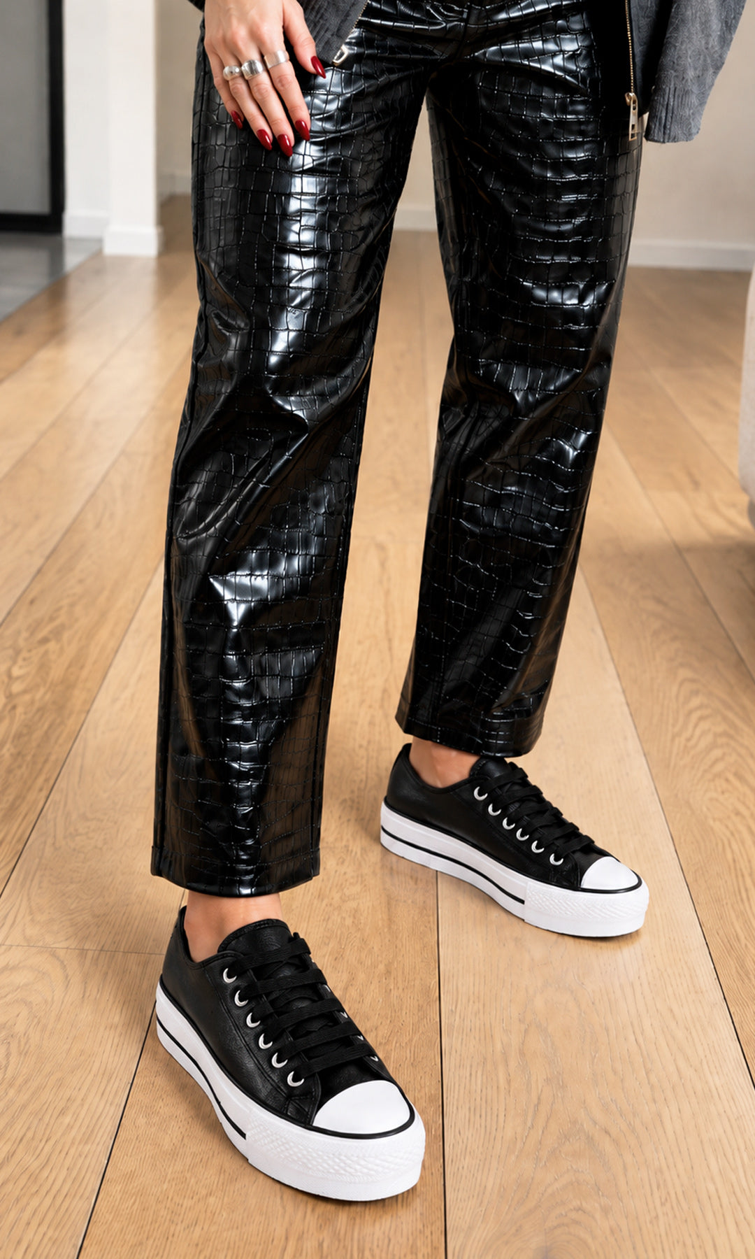 Tenis negros de plataforma con agujetas, puntera blanca y suela gruesa, combinados con pantalón negro de acabado brillante para un look casual moderno