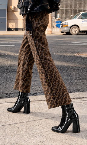 Botines Toffee negros de charol con tacón ancho alto y punta redondeada, combinados con pantalón estampado en un look urbano