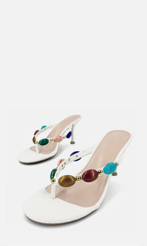 Par de sandalias de tacón tipo thong TRIBECCA BLANCO de vinipiel en vista 3/4, con joyería 3D multicolor en las tiras y tacón fino de 8 cm