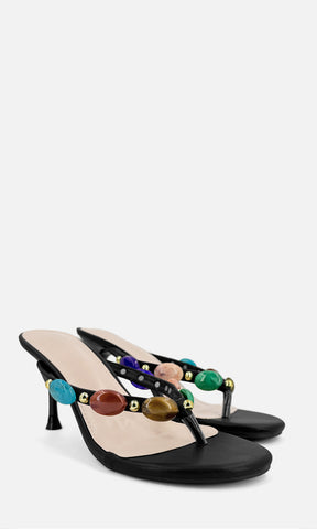 Par de sandalias de tacón tipo thong TRIBECCA NEGRO de vinipiel en vista 3/4, con joyería 3D multicolor en las tiras y tacón fino de 8 cm