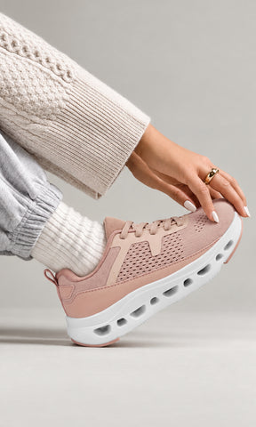 Tenis deportivos rosa nude con tejido transpirable y suela blanca gruesa, combinados con pantalón jogger gris, calcetas claras y suéter de punto para mujer