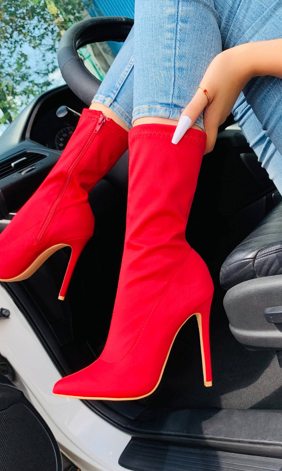 MADONA MUJER LUCIENDO BOTINES ALTOS DE LICRA ROJA CON SKINNY JEANS EN CARRO